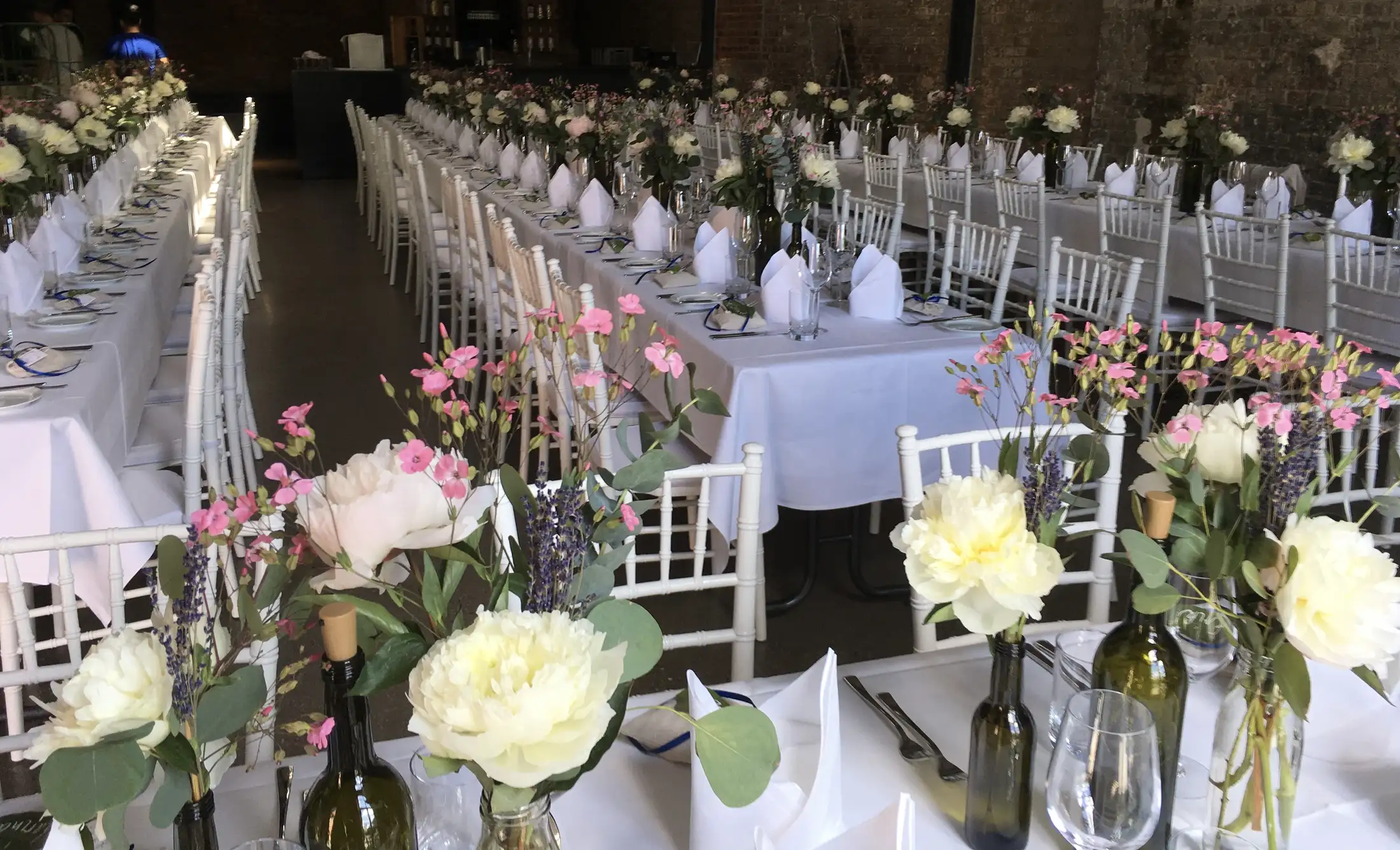 Festtafeln einer Hochzeit mit Blumenschmuck in Flaschen und Vasen