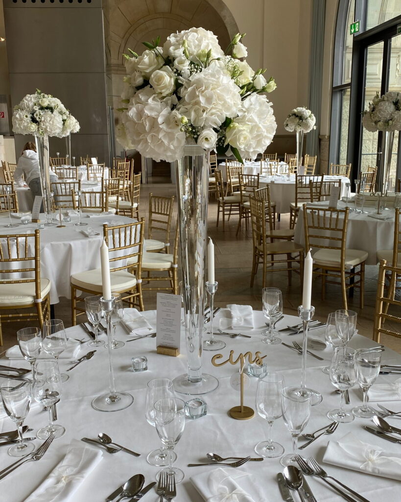 Festtafel mit weißen Blütenkugeln auf hohen Glasvasen