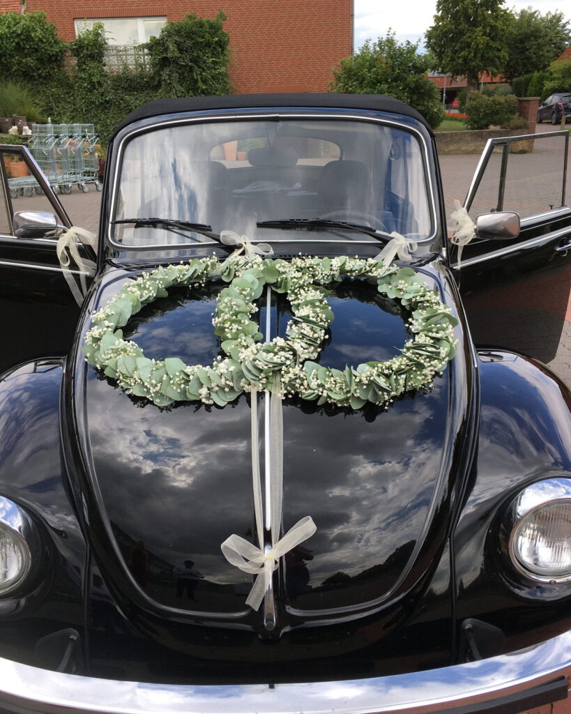 VW Käfer Cabrio mit herzförmigem Blumenkranz als Autoschmuck